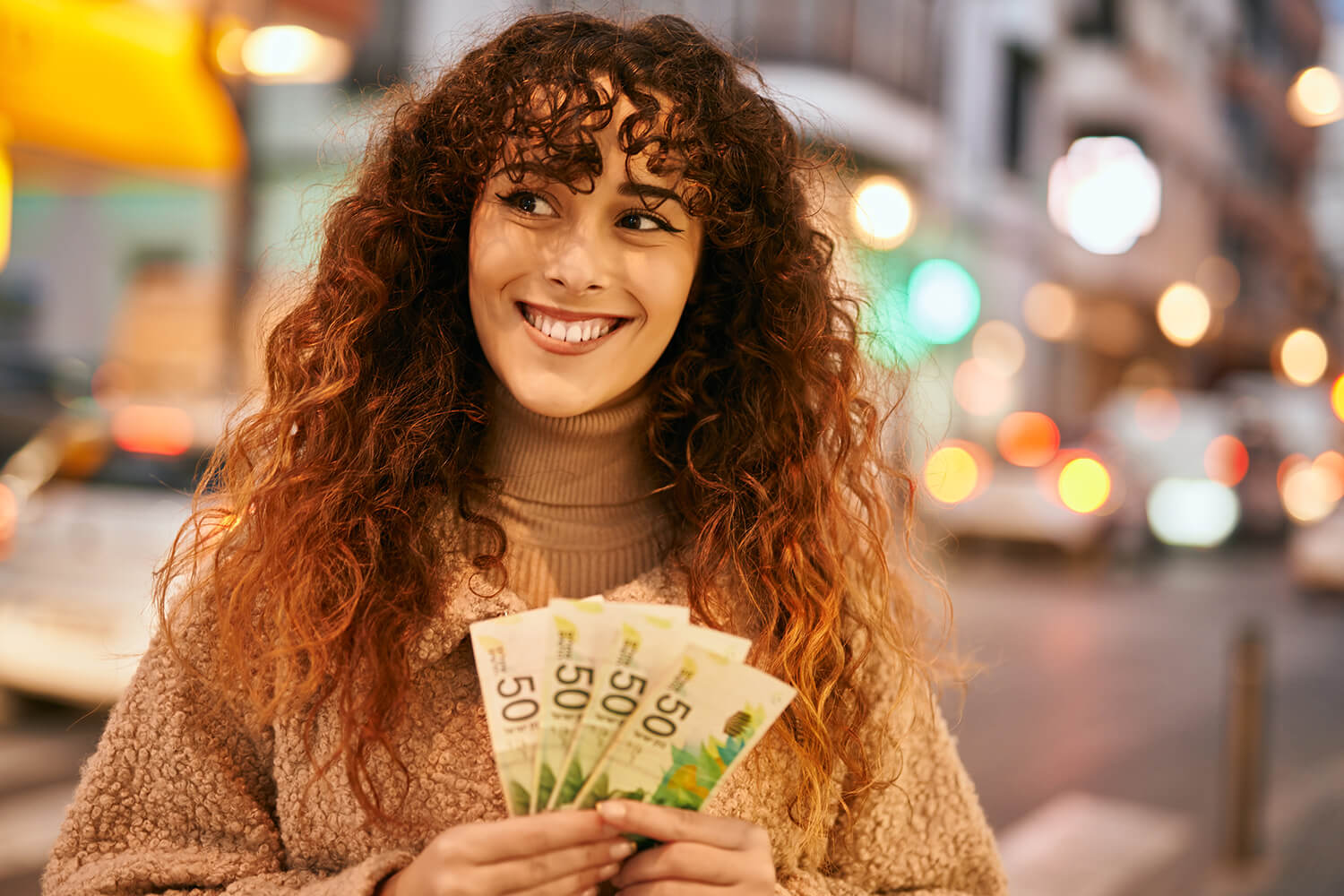 Femme en pleine rue qui tient des billets de banque